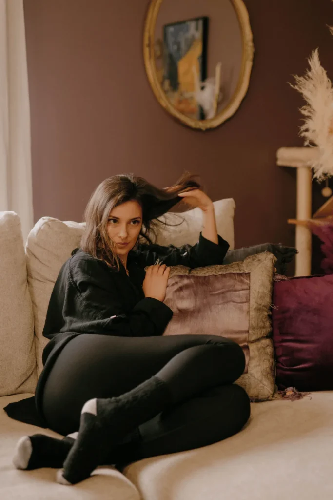 image of a girl sitting on a couch flipping her hair as she's looking off into the distance